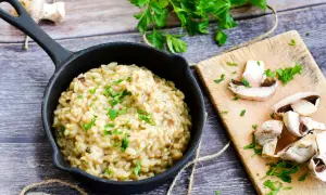 Kremowe risotto z grzybami, posypane natką pietruszki. Idealny przepis na pyszny obiad.