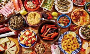 Tapas co to? Kolorowy stół pełen hiszpańskich przekąsek: kiełbaski, krewetki, kalmary, owoce morza, ser, tortilla i wędliny.