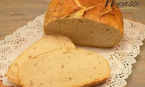 Pyszny, pachnący chleb domowy z makiem, pokrojony na kromki, leży na ozdobnej serwetce.