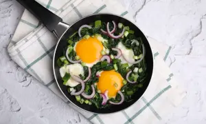 Pyszna szakszuka ze szpinakiem, jajkami sadzonymi, cebulką i serem feta na patelni. Idealna na śniadanie.