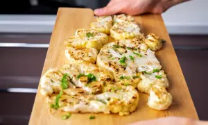 Kotleciki z kalafiora, pieczone na desce, posypane zieloną pietruszką. Pyszne i zdrowe danie.