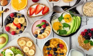 Kolorowe śniadanie dla dzieci: owsianka z owocami, tosty z awokado i jajkiem, płatki z jagodami, smoothie, jajka sadzone z awokado i sok pomarańczowy.