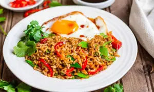 Nasi goreng z jajkiem sadzonym, papryką i zielonym groszkiem, ozdobione kolendrą. Pyszne danie, które rozgrzeje każde podniebienie.