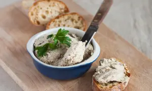 Pyszna pasta z gotowanego kurczaka na chrupiącym pieczywie, udekorowana natką pietruszki. Idealna na przekąskę.