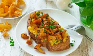 Tost z jajecznicą i kurkami, posypany ziołami. Pyszne danie na śniadanie lub lekki posiłek.