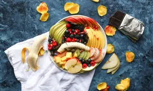 Kolorowa taca z owocami: jabłka, gruszki, kiwi, mango, maliny, borówki, jeżyny i granat. Idealny sposób, jak podać owoce na imprezie.