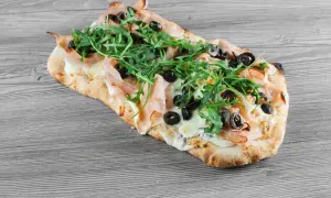 Pinsa z szynką, mozzarellą, rukolą i oliwkami. Idealny przepis na pinsę, który zachwyci każdego.