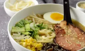 Pyszny ramen przepis: miska pełna makaronu, jajko na twardo, plastry boczku, warzywa i kiełki. Idealny na chłodne dni.