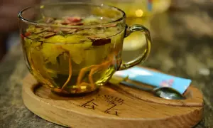 Aromatyczna herbata z dodatkiem imbiru do herbaty, kwiatów i jagód. Podana w szklanej filiżance na drewnianej podstawce.