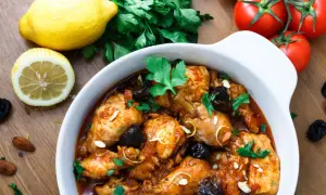 Aromatyczny tagine z kurczakiem, śliwkami i migdałami, podany z cytryną i pomidorami.