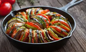 Ratatouille w żeliwnej patelni, klasyka kuchni francuskiej. Warzywa ułożone wachlarzowo, skropione ziołami.