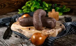 Dwie porcje kaszanki na desce, obok cebula i przyprawy. Zastanawiasz się, czy kaszankę można zamrozić? Tak, można!