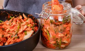 Przygotowanie kimchi: kapusta pekińska z sosem czosnkowo-paprykowym w misce i słoiku.