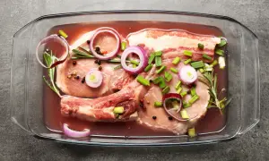 Peklowanie mięsa do pieczenia w szklanym naczyniu z cebulą, rozmarynem i pieprzem.