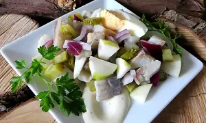 Sałatka ze śledzi z ogórkiem kiszonym, jabłkiem i czerwoną cebulą, podana z majonezem i jajkiem.