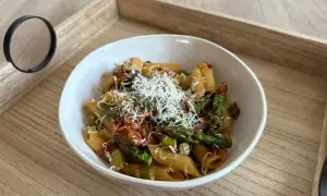 Penne z zielonymi szparagami i suszonymi pomidorami, posypane tartym parmezanem. Pyszne danie, które zachwyci każdego miłośnika makaronów.