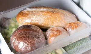 Jak mrozić chleb? W zamrażarce leżą zawinięte w folię bochenki i bułki, obok woreczki z mrożonymi warzywami.