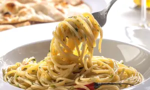 Pyszny, aromatyczny makaron spaghetti z czosnkiem i chili, idealny przepis na szybki makaron. Na talerzu widać też pieczywo.