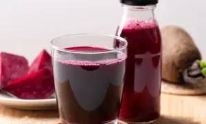 Szklanka i butelka z buraczanym sokiem, obok talerz z kawałkami buraka. Idealny sok z buraka przepis na zdrowie.