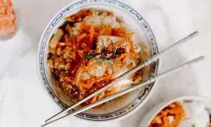 Miseczka ryżu z pikantnym kimchi i marchewką, pałeczki gotowe do jedzenia. Kimchi co to? To fermentowana kapusta.