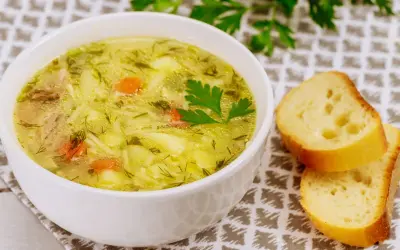 Aromaticzna zupa wiosenna z kawałkami kurczaka, ziemniaków i marchewki, posypana świeżym koperkiem. Obok kromki chleba.