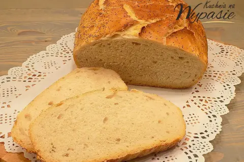 Pyszny, pachnący chleb domowy z makiem, pokrojony na kromki, leży na ozdobnej serwetce.