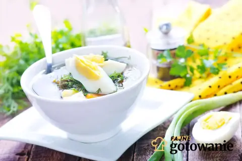 Aromaticzna zupa koperkowa z jajkiem i zieloną cebulką, podana w białej miseczce na drewnianym stole.