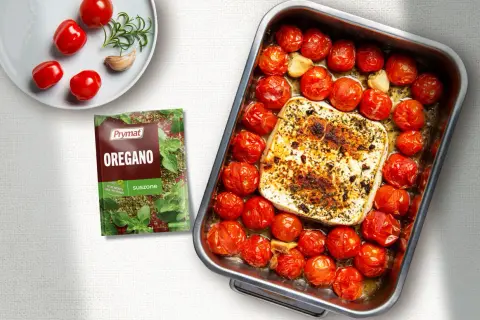 Pieczona feta z pomidorami i czosnkiem, doprawiona oregano. Pyszne danie gotowe do podania.