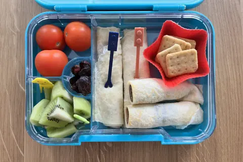 Kolorowe kanapki dla dzieci w pudełku: naleśniki z czekoladą, kiwi, pomidorki i ciasteczka.