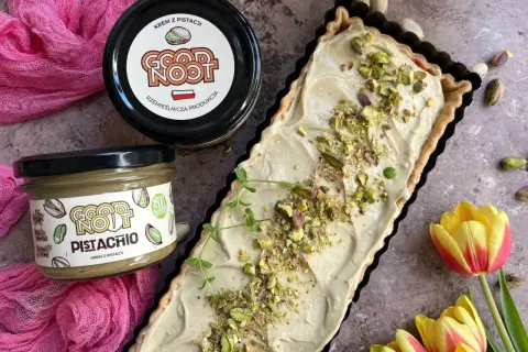 Nowoczesny mazurek wielkanocny z kremem pistacjowym. Idealny na święta, udekorowany pistacjami i gałązką mięty.