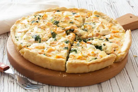 Pyszna tarta z łososiem, szpinakiem i serem feta, pokrojona na kawałki, gotowa do podania.