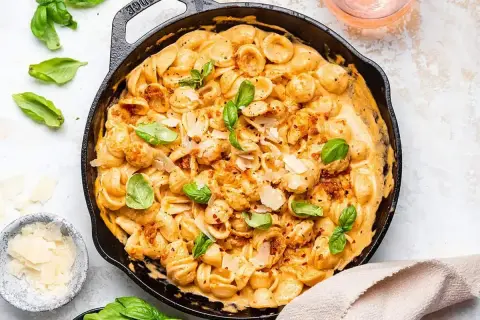 Orecchiette w kremowym sosie z suszonych pomidorów, posypane parmezanem i świeżą bazylią. Pyszne danie, które zachwyci każdego.