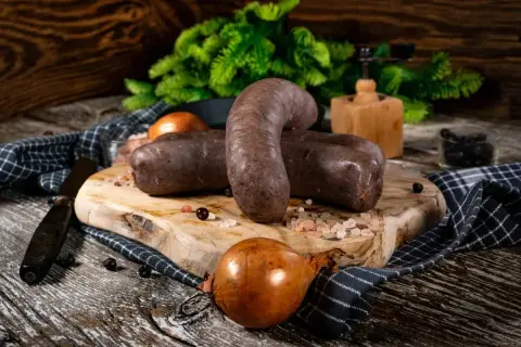 Dwie porcje kaszanki na desce, obok cebula i przyprawy. Zastanawiasz się, czy kaszankę można zamrozić? Tak, można!