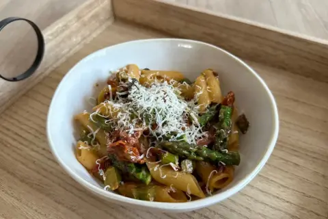 Penne z zielonymi szparagami i suszonymi pomidorami, posypane tartym parmezanem. Pyszne danie, które zachwyci każdego miłośnika makaronów.
