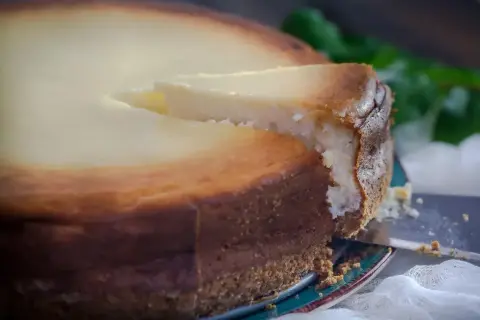 Idealny sernik, który nie opadł, z wyciętym kawałkiem. Poznaj sekrety, co zrobić żeby sernik nie opadł i cieszyć się jego perfekcyjnym wyglądem.