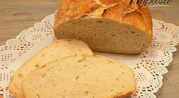 Pyszny, pachnący chleb domowy z makiem, pokrojony na kromki, leży na ozdobnej serwetce.