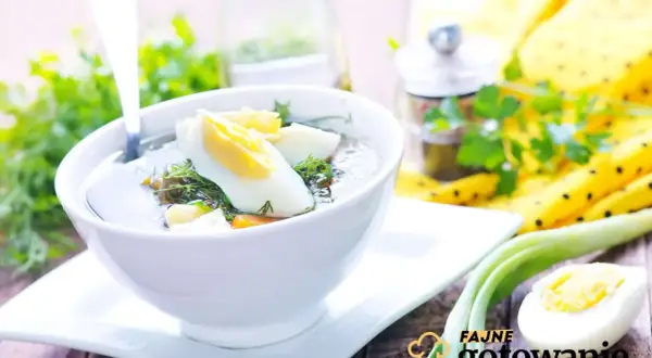 Aromaticzna zupa koperkowa z jajkiem i zieloną cebulką, podana w białej miseczce na drewnianym stole.