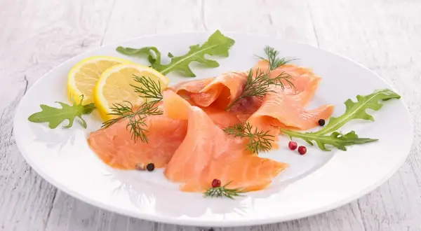 Eleganckie carpaccio z łososia, ozdobione rukolą, cytryną i koperkiem, kusi delikatnym smakiem.