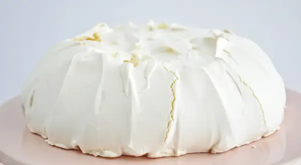 Puszysta beza pavlova z kremem, gotowa do dekoracji owocami.
