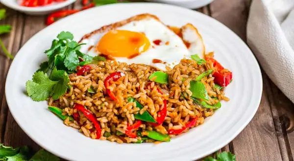 Nasi goreng z jajkiem sadzonym, papryką i zielonym groszkiem, ozdobione kolendrą. Pyszne danie, które rozgrzeje każde podniebienie.