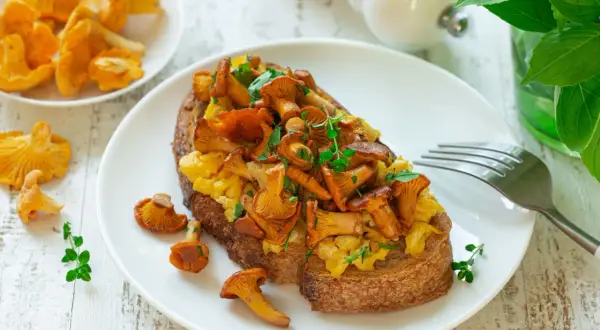 Tost z jajecznicą i kurkami, posypany ziołami. Pyszne danie na śniadanie lub lekki posiłek.