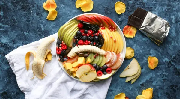 Kolorowa taca z owocami: jabłka, gruszki, kiwi, mango, maliny, borówki, jeżyny i granat. Idealny sposób, jak podać owoce na imprezie.