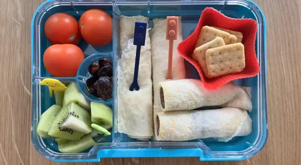 Kolorowe kanapki dla dzieci w pudełku: naleśniki z czekoladą, kiwi, pomidorki i ciasteczka.