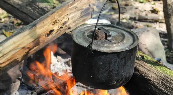 Czajnik wisi nad ogniskiem, gotując pyszne dania z ogniska. Płomienie tańczą pod garnkiem, tworząc magiczną atmosferę.