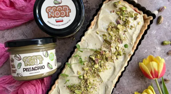 Nowoczesny mazurek wielkanocny z kremem pistacjowym. Idealny na święta, udekorowany pistacjami i gałązką mięty.
