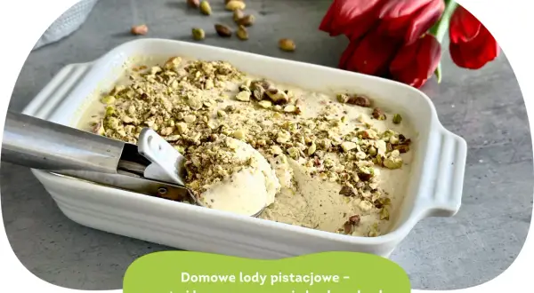 Domowe lody pistacjowe w białej misce, posypane orzechami. Obok czerwone tulipany i gałka lodów na łyżce.