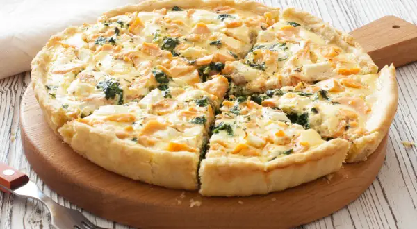 Pyszna tarta z łososiem, szpinakiem i serem feta, pokrojona na kawałki, gotowa do podania.