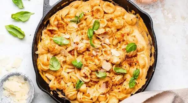 Orecchiette w kremowym sosie z suszonych pomidorów, posypane parmezanem i świeżą bazylią. Pyszne danie, które zachwyci każdego.