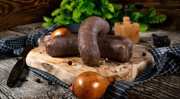 Dwie porcje kaszanki na desce, obok cebula i przyprawy. Zastanawiasz się, czy kaszankę można zamrozić? Tak, można!