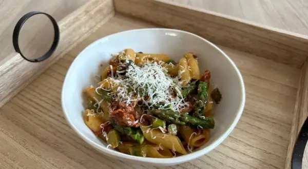 Penne z zielonymi szparagami i suszonymi pomidorami, posypane tartym parmezanem. Pyszne danie, które zachwyci każdego miłośnika makaronów.